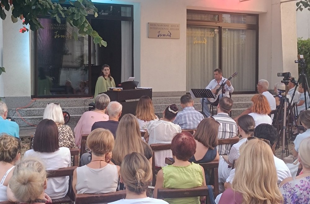 A summer concert in the garden of the Ismet Mujezinović Atelier, musicians on the steps and an audience on chairs