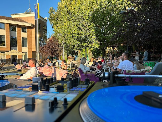 A DJ mixer and a record in front of a full terrace at Cafe Sloboda on a summer evening