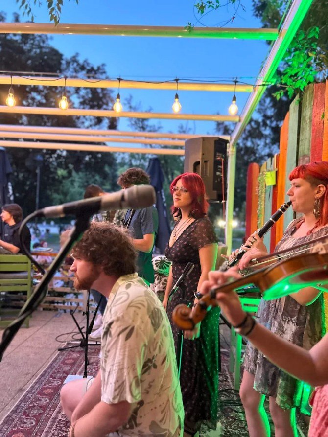 A band (singer, violin and clarinet) playing on the bar's garden terrace under string lights in the evening
