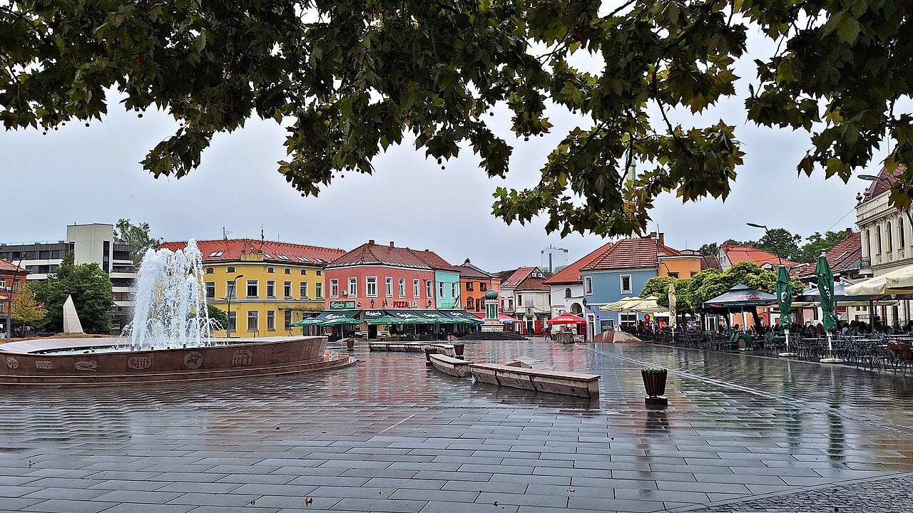 Freedom Square after rain: the fountain, café umbrellas and the coloured houses of the square