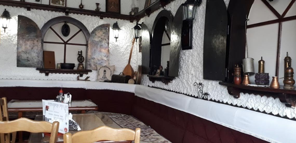 The restaurant's interior in traditional Bosnian style, with copper vessels and old objects on white walls above the seating
