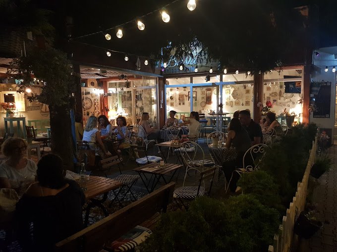 The Coffee Zone summer garden at night under string lights, with guests at tables in front of the cafe's glass front