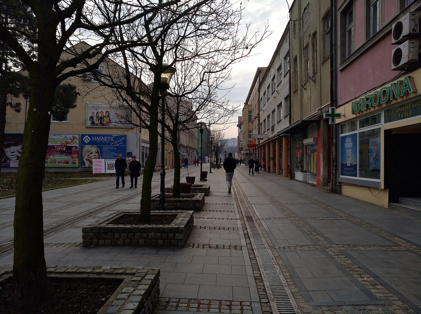 The pedestrian street Turalibegova in Tuzla on a winter day, with bare trees, planters and shopfronts