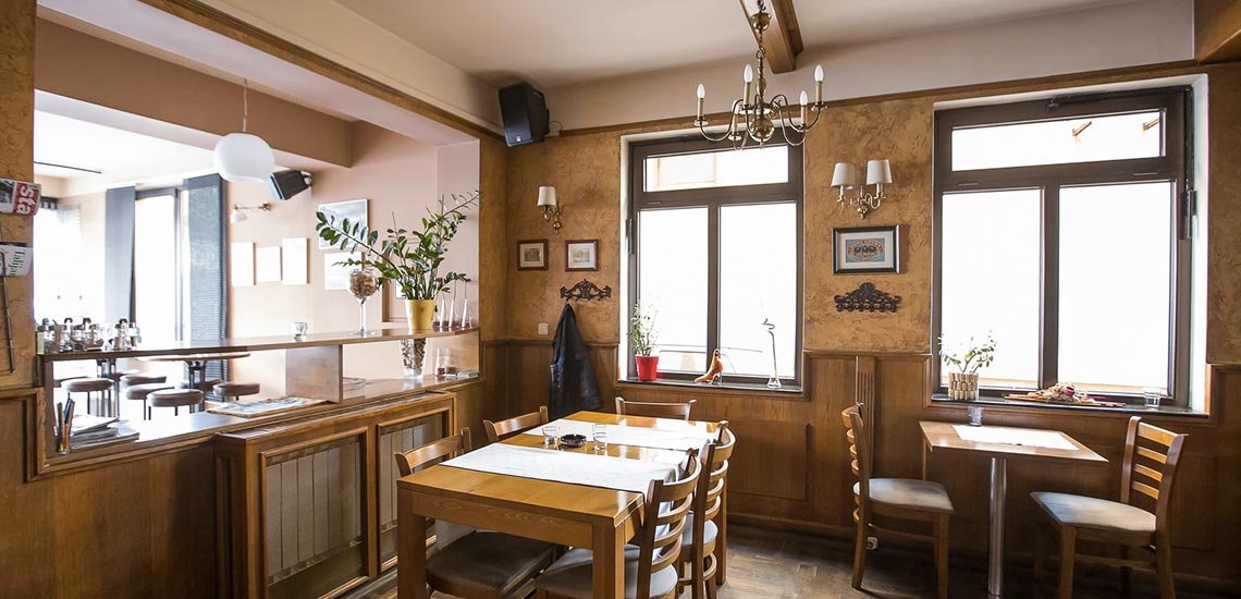 The Heartland dining room: wooden tables, a chandelier and windows on two sides