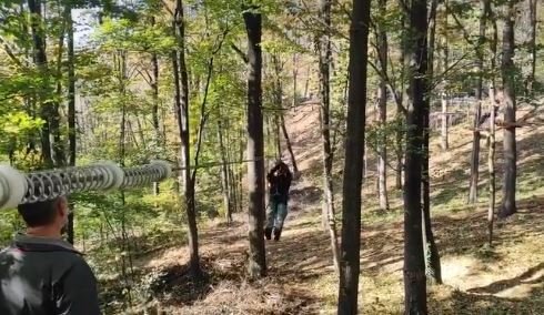 A zip-line through the woods on Ilinčica hill, a person climbing between the trees