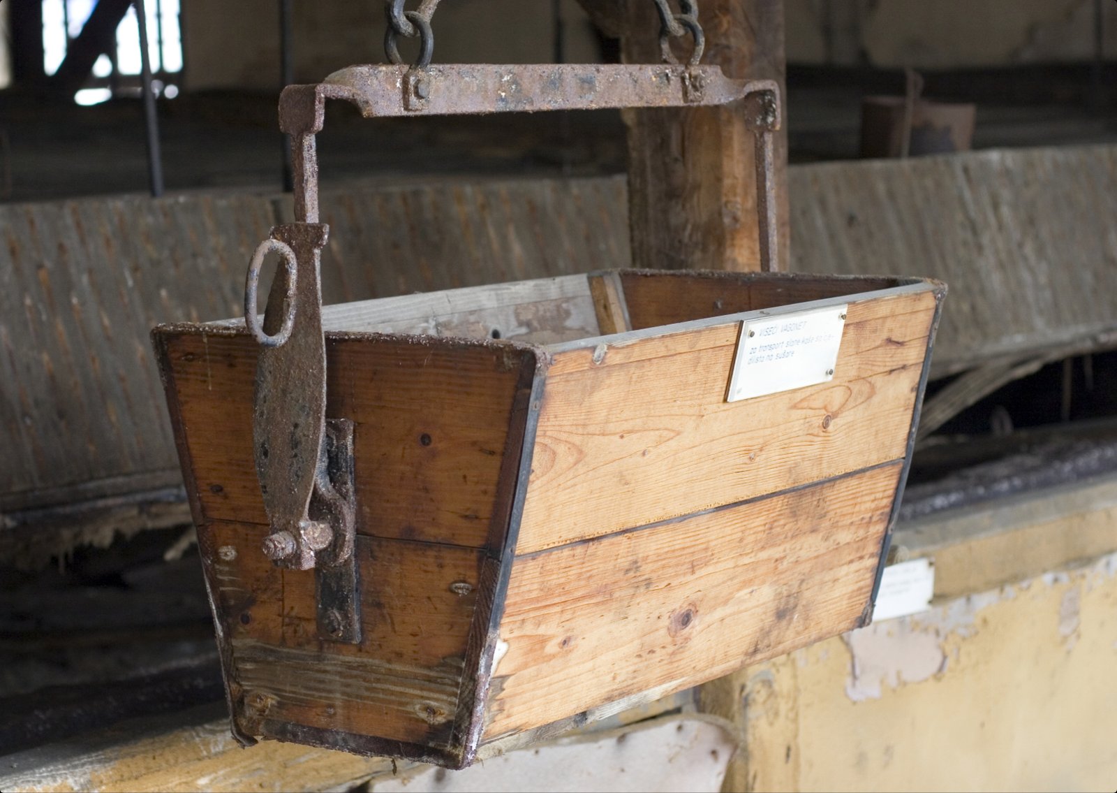 A wooden salt-carrying box hanging from a metal hook inside the old saltworks museum