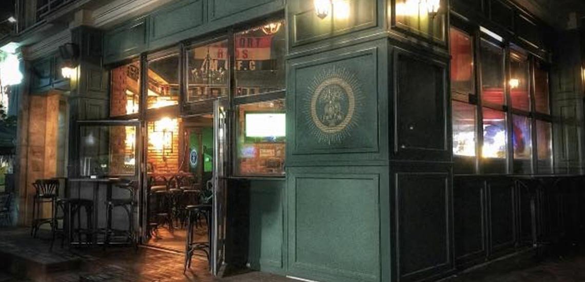 The green wooden front of Park Pub at night, its windows lit