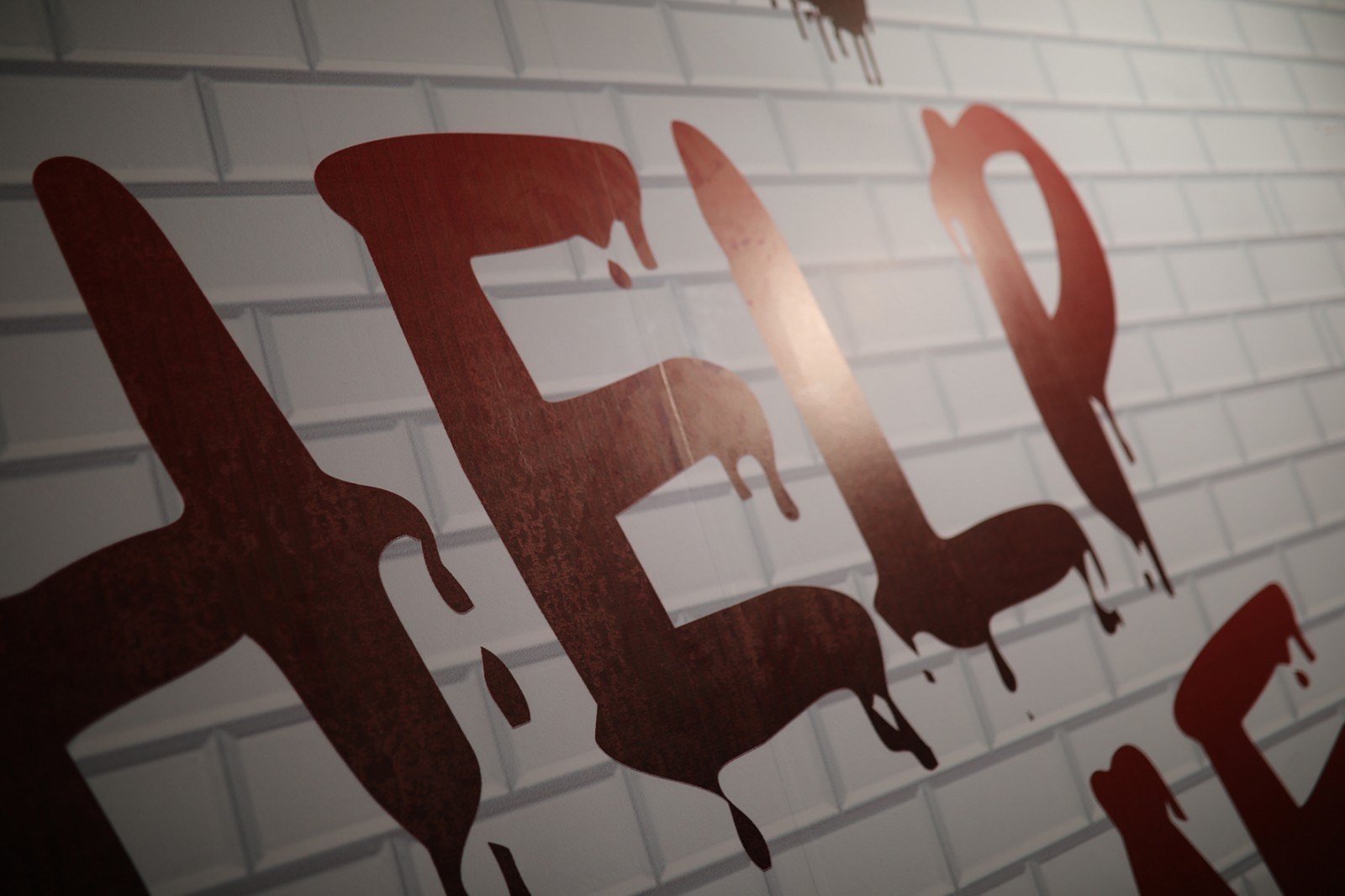 A white-tiled wall in one of the escape rooms, splashed with fake red blood and lit by a red lamp