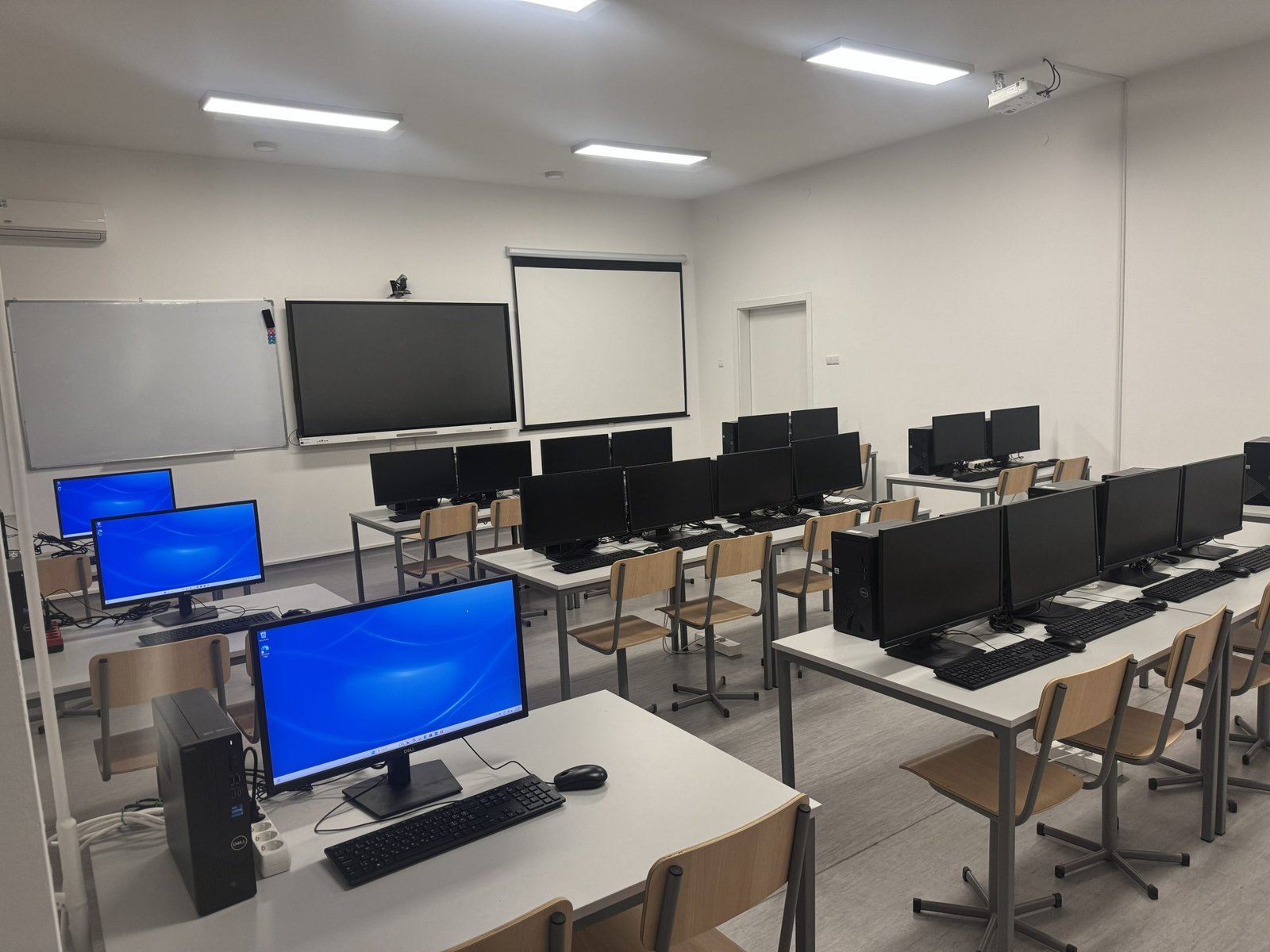 The empty INTERBA Laboratory computer centre with rows of desks, desktop computers, a whiteboard, a wall screen and a projection screen