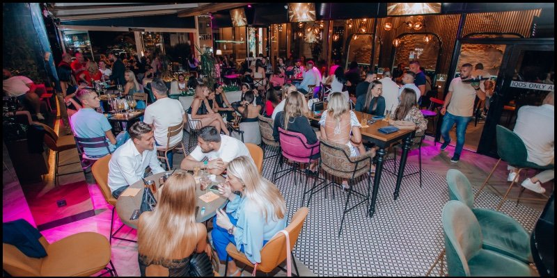 People at tables under pink lights in WINT Lounge Bar